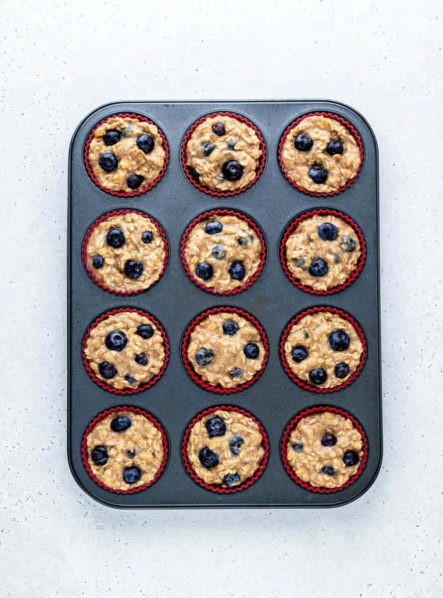 Muffin mixture spooned into a muffin tin.