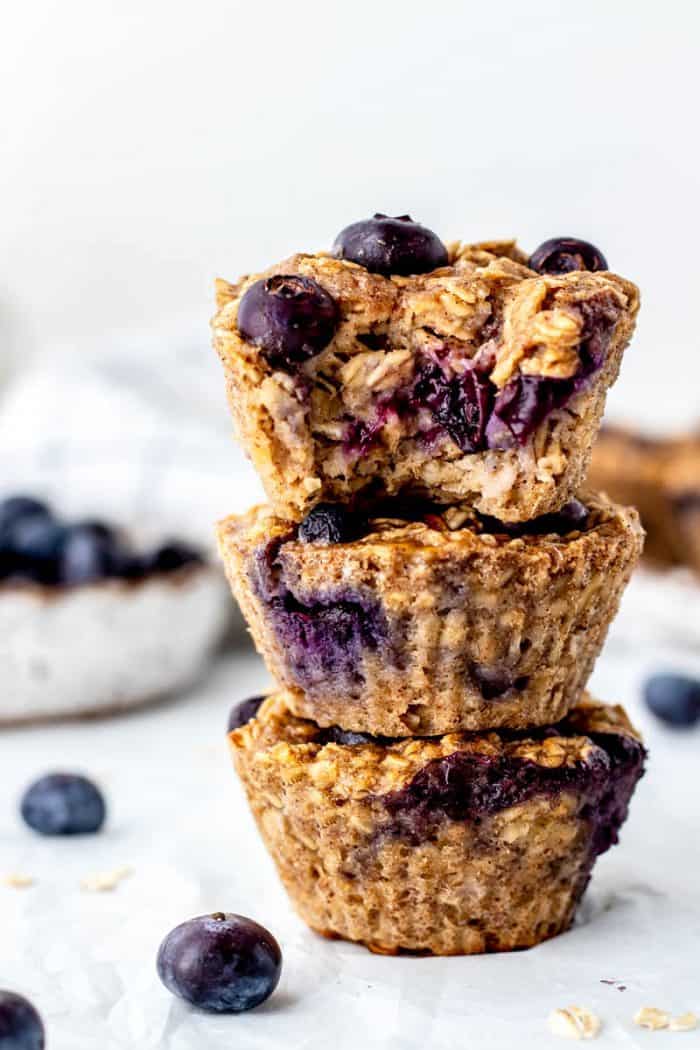 Three blueberry banana oatmeal muffins on top of each other with a bite taken out of the top one.