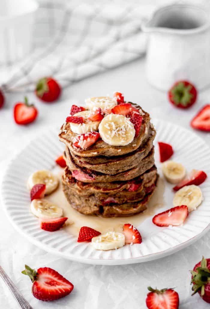 Oatmeal strawberry banana pancakes stacked on a plate.