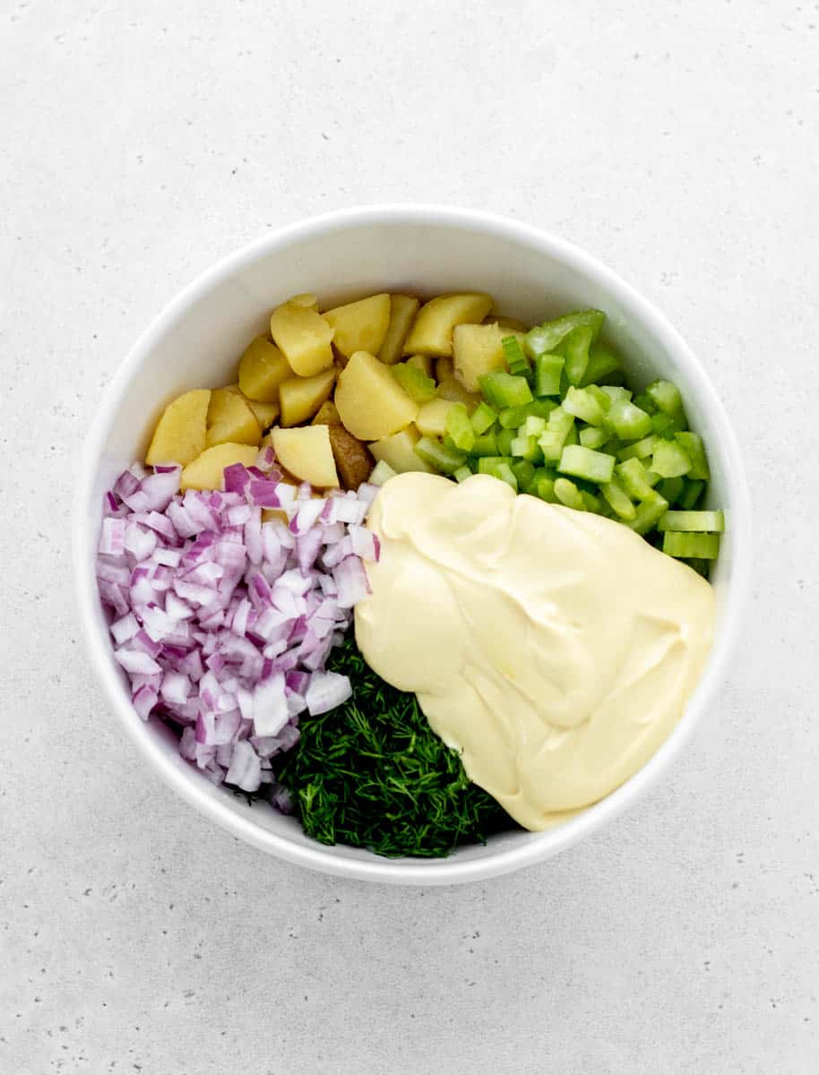 Dill potato salad ingredients added to a large bowl.