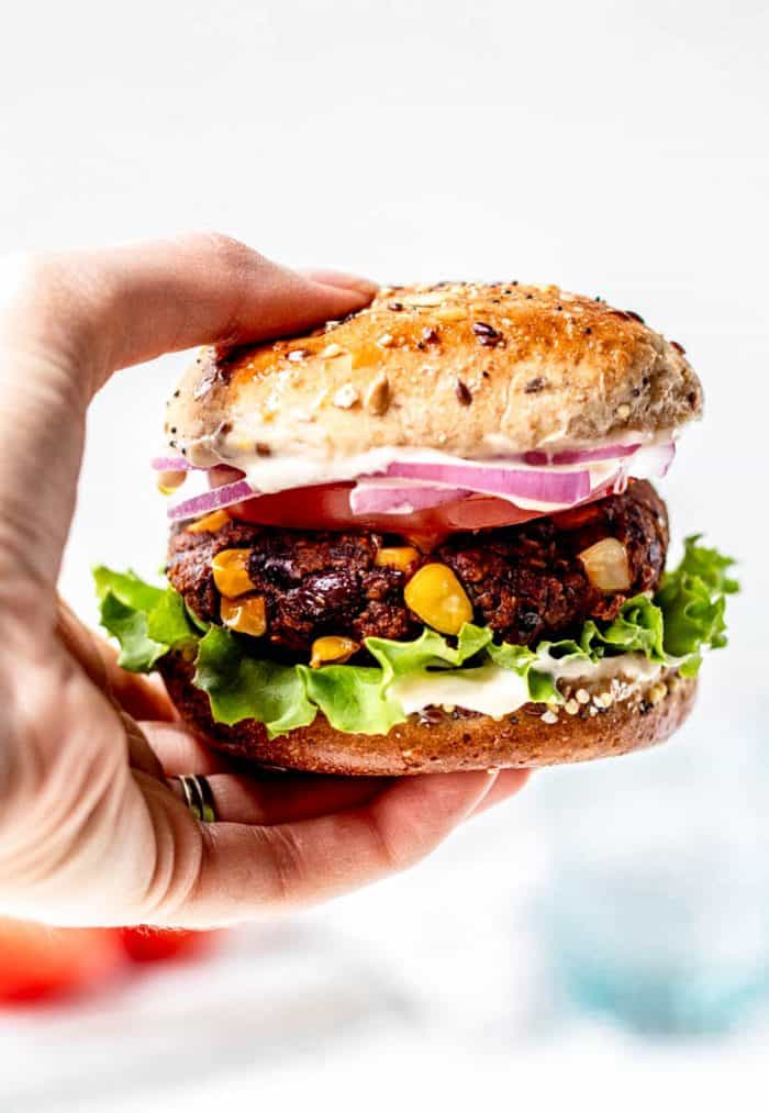 A hand holding a vegan spicy black bean burger.