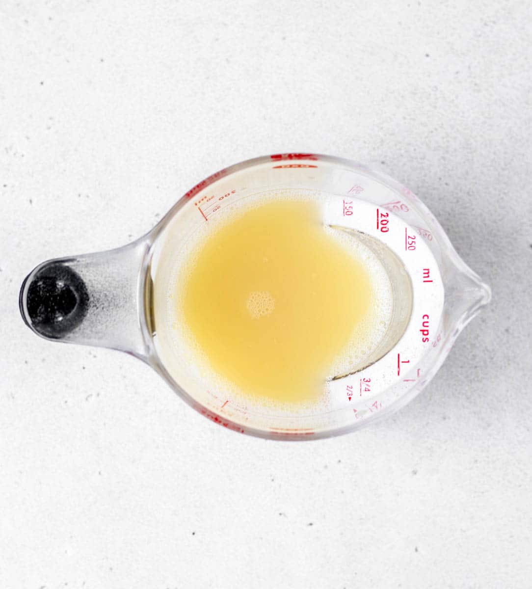 Pineapple juice mixed with cornstarch in a measuring cup.