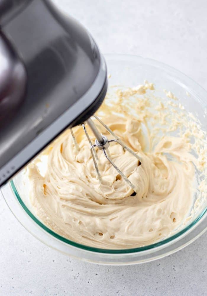 A hand mixer blending the cream cheese and maple syrup.