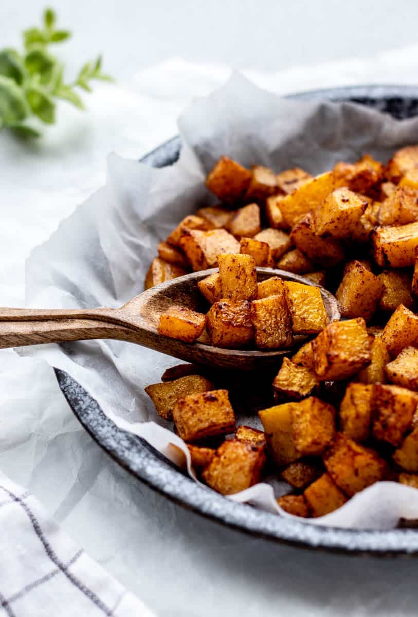 Roasted air fryer butternut squash cubes in a bowl with a spoon lifting some up.