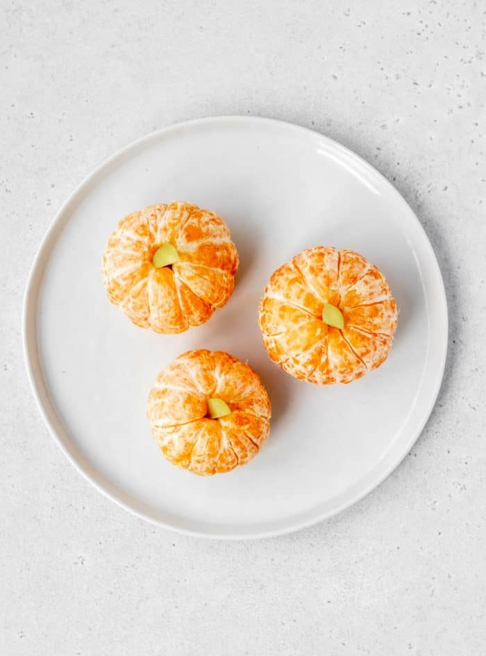 Clementine pumpkins on a white plate.