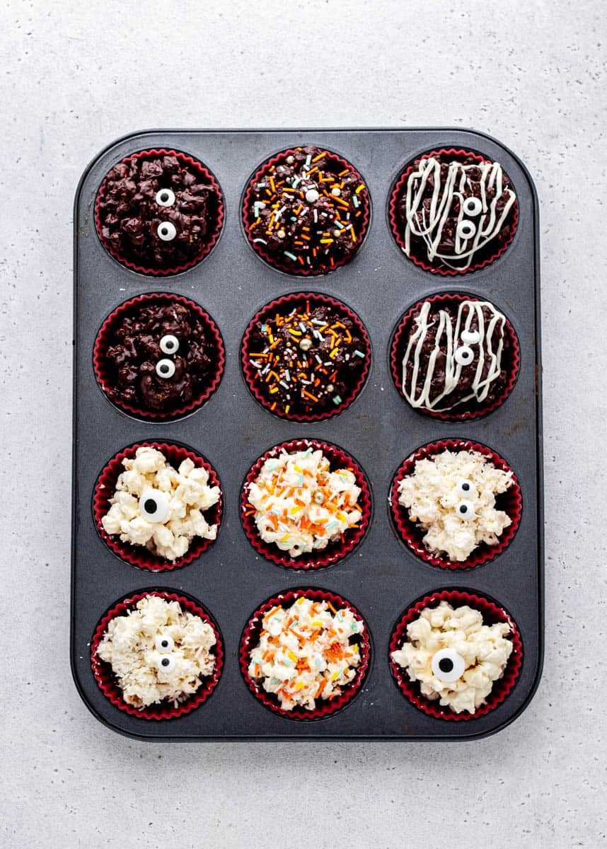 A lined muffin tin full of chocolate Halloween popcorn balls.