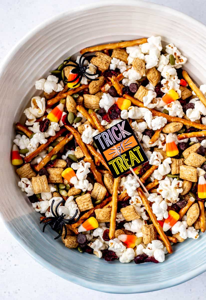 A close up of a large bowl filled with Halloween trail mix and a trick or treat sign.