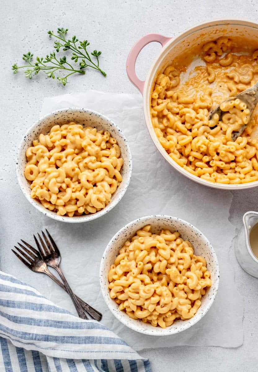 Overhead image of two bowls of homemade macaroni and cheese next to a pot of mac and cheese.