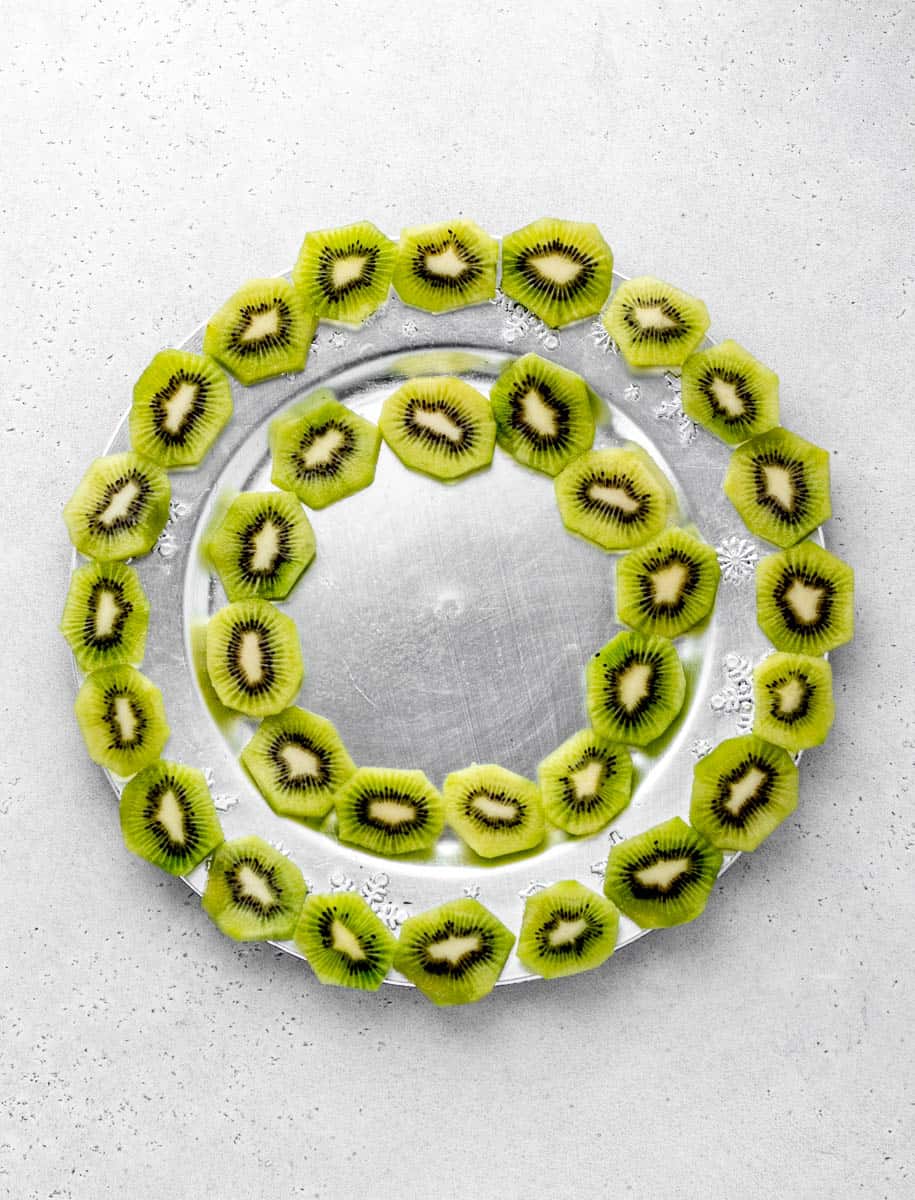 Sliced kiwis line the outer and inner circle of the Christmas fruit wreath.