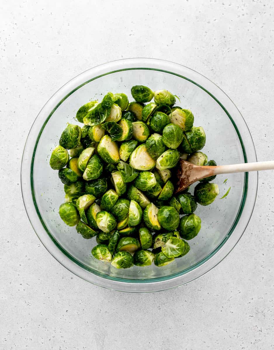 A glass bowl of halved brussel sprouts.