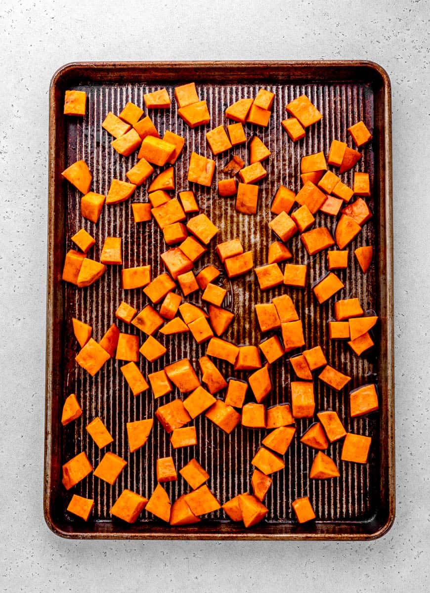 A sheet pan of cubed sweet potato, spread in an even layer.