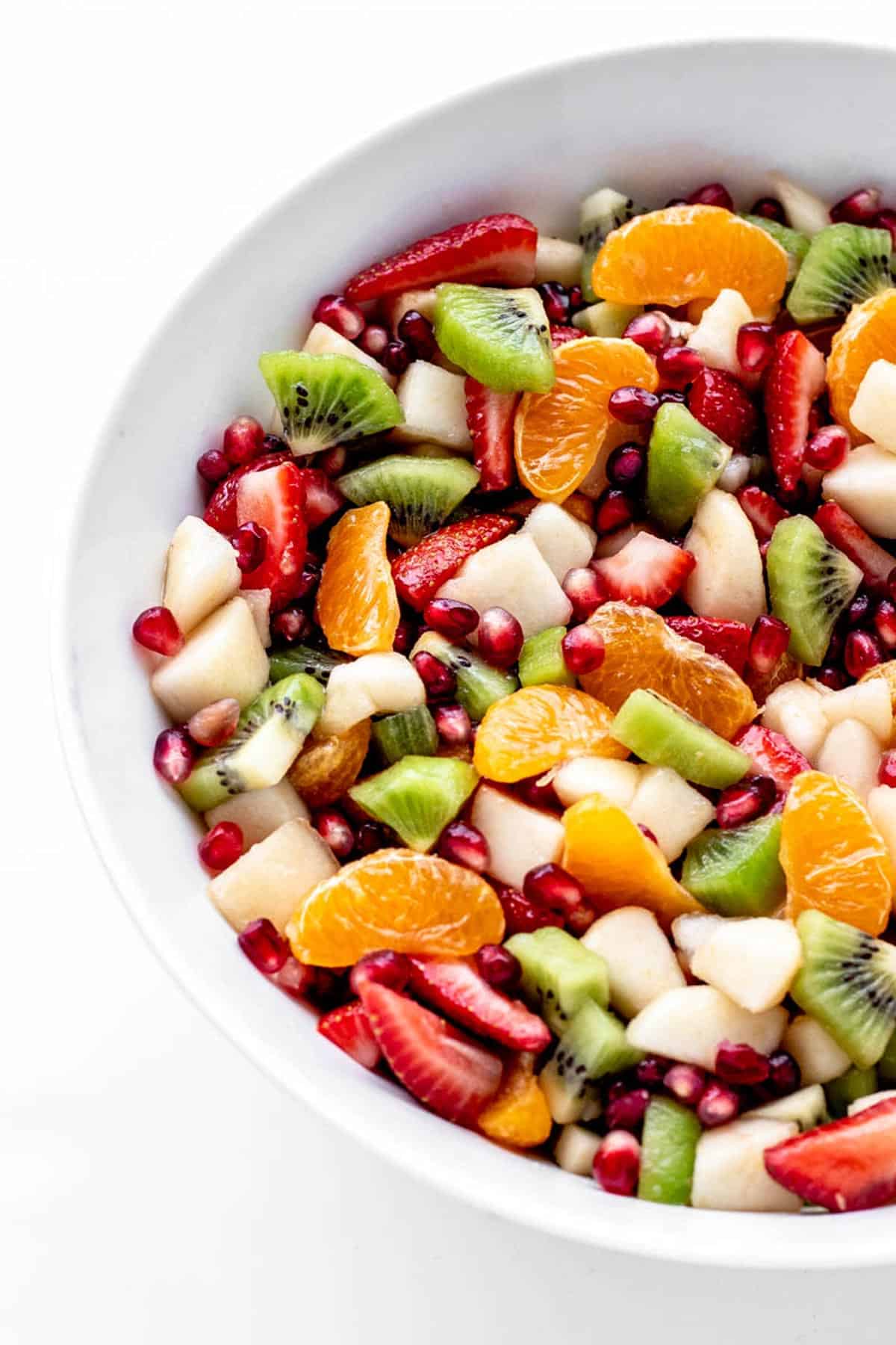 A closeup of Christmas breakfast fruit salad in a white serving bowl.