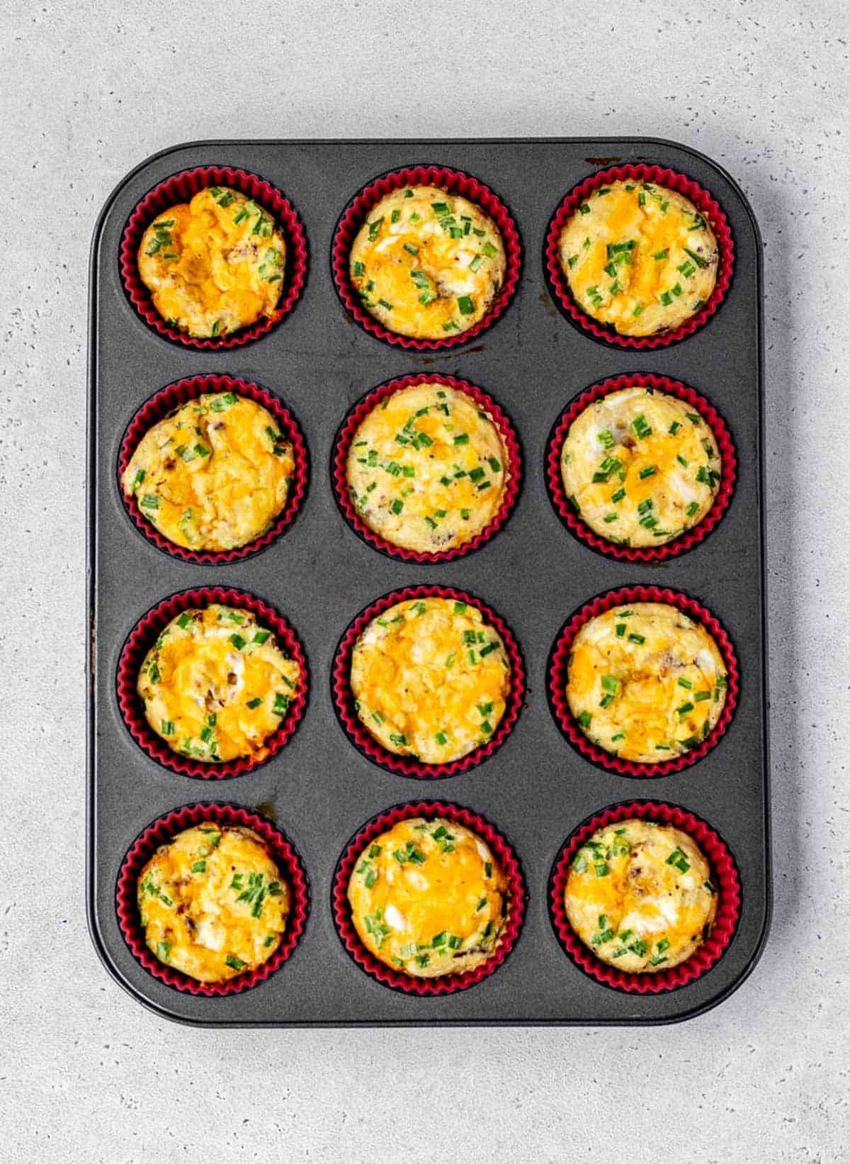 A 12 cup muffin tin of baked mini crustless quiches.