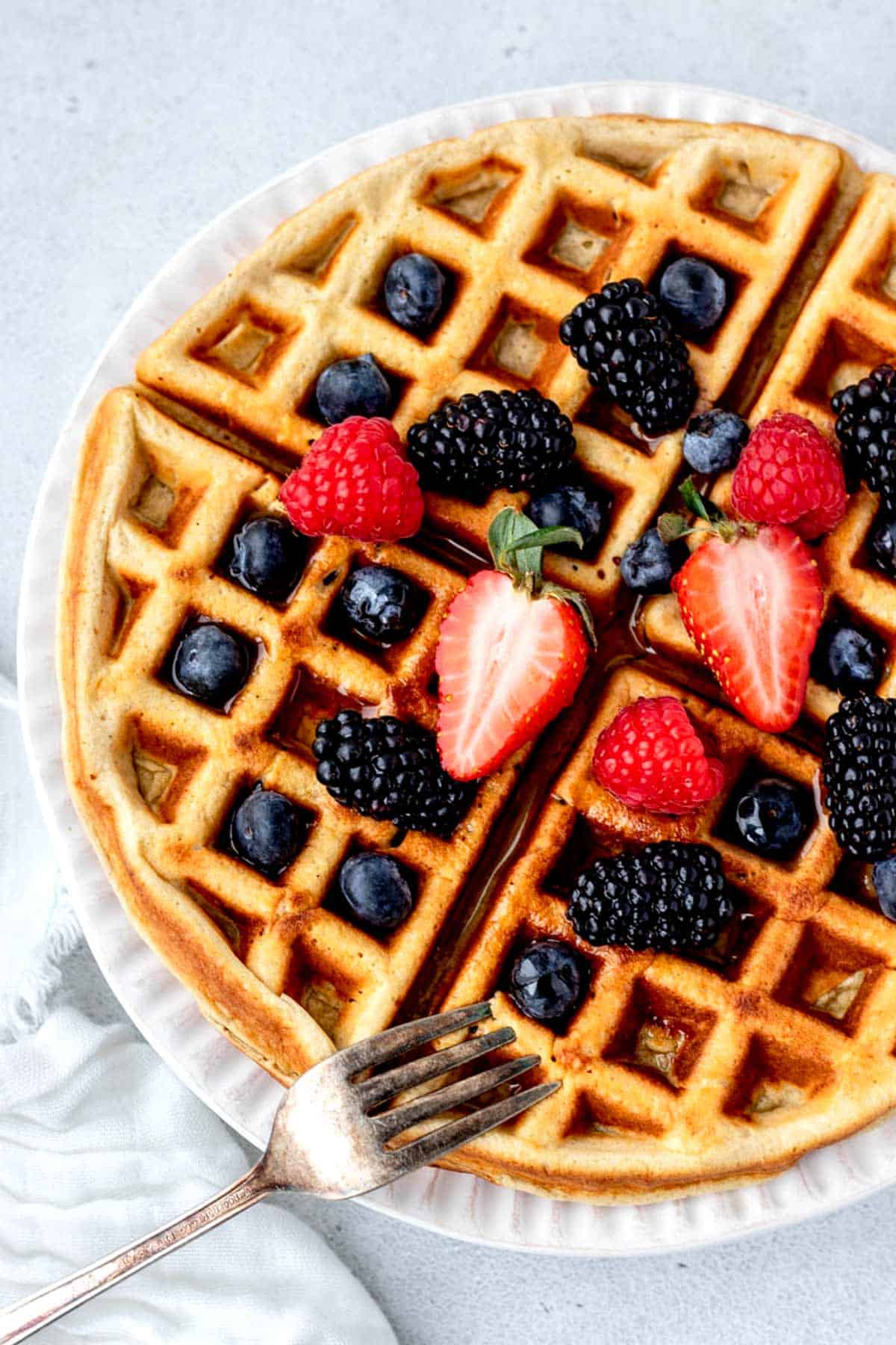 A high protein waffle, topped with mixed berries and maple syrup.
