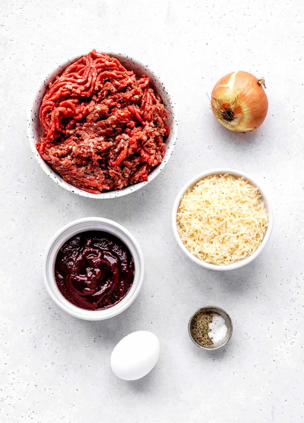 Ingredients for 5 ingredient meatloaf including lean ground beef, egg, salt, pepper, parmesan cheese, BBQ sauce and onion.