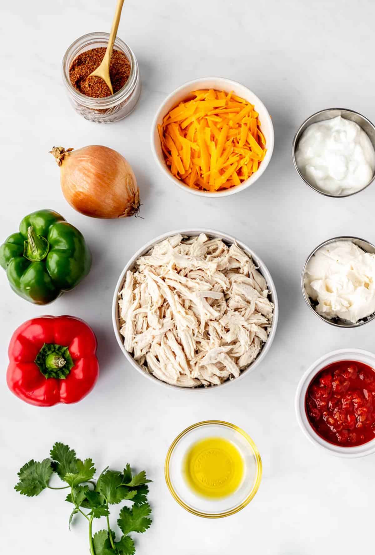 Ingredients for low carb chicken fajita casserole, including salsa, shredded chicken, bell pepper, cream cheese, Greek yogurt, shredded cheese and onion.