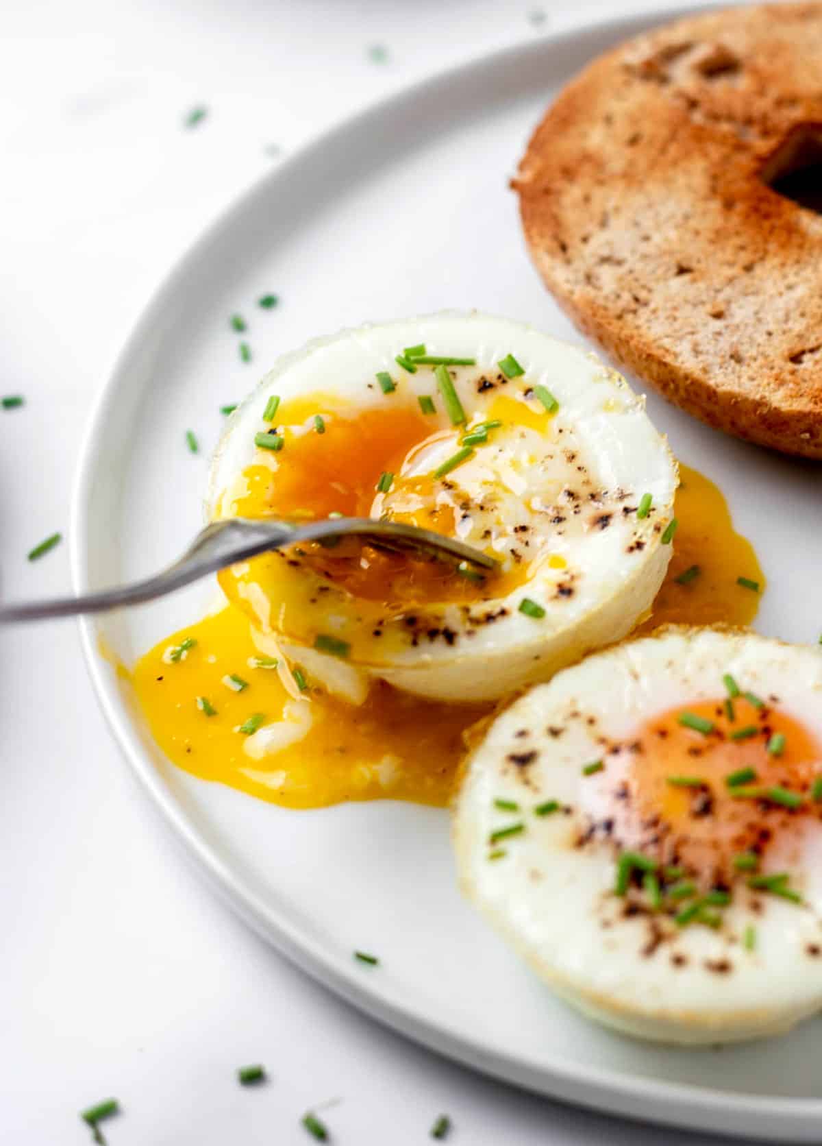 A fork poking into a baked egg with yolk running out.