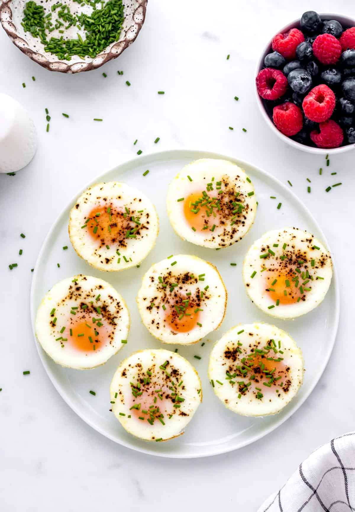 Oven baked eggs on a plate sprinkled with chives.
