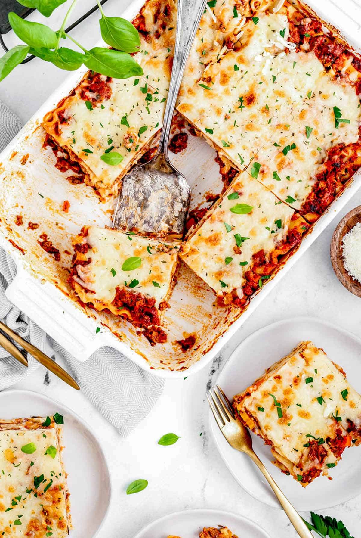 Overhead image of a slice of lasagna being lifted out of a baking pan with a spatula