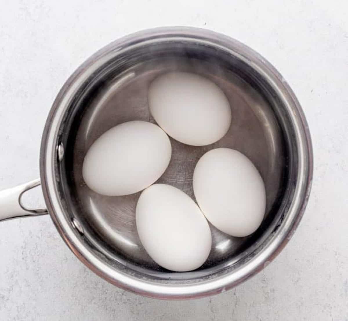 Four hard boiled eggs in a small sauce pan.