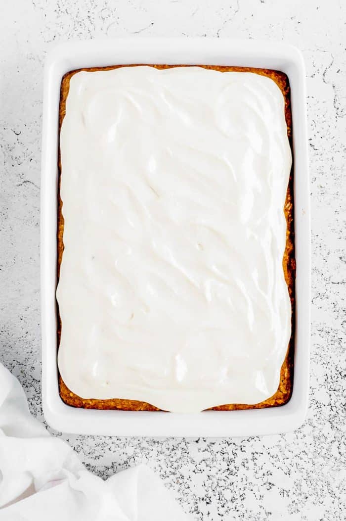 The carrot cake iced in a large rectangular baking dish. 