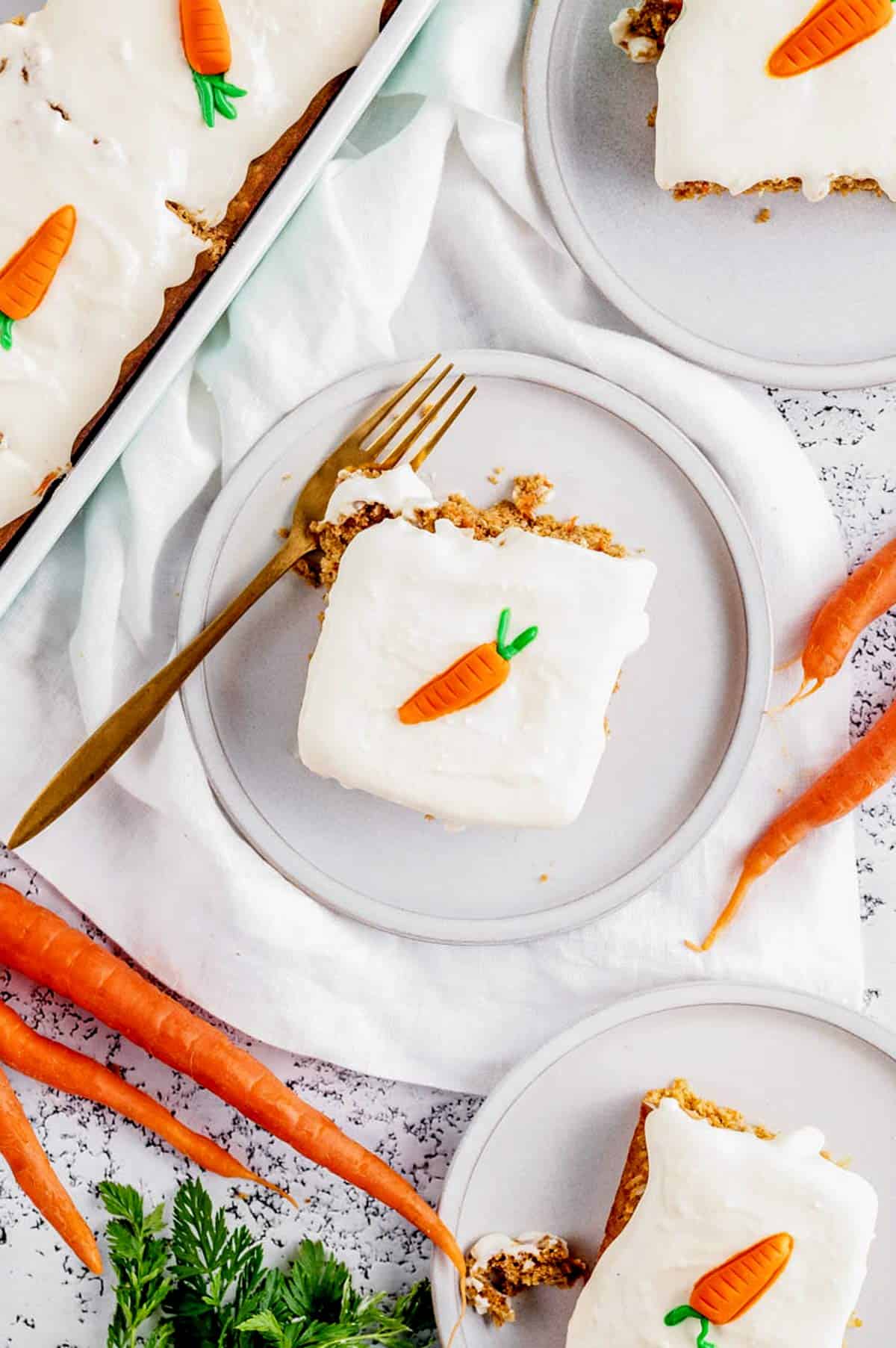 Overhead image of slices of carrot cake on three small plates.