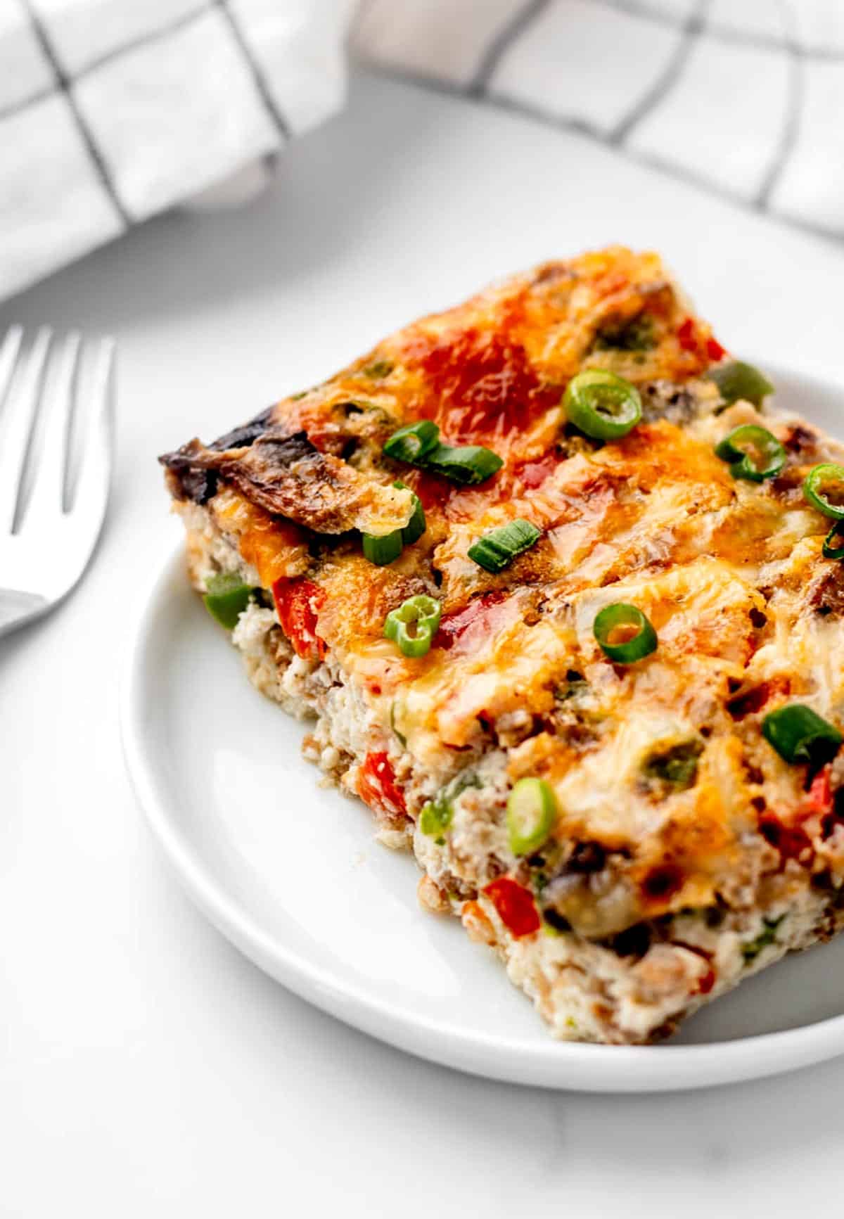 A slice of egg white and sausage breakfast casserole on a white plate.