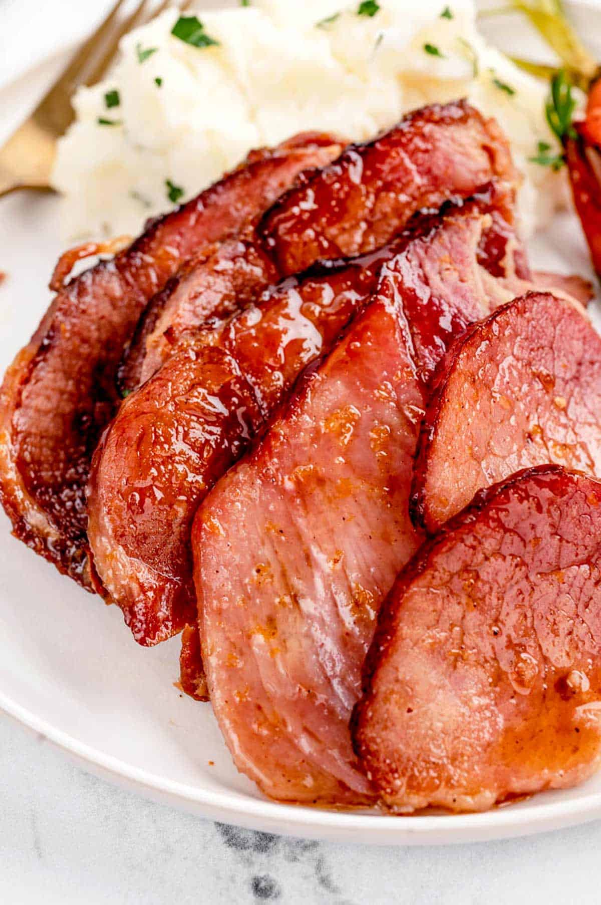 Up close image of glazed ham slices cut on a plate.